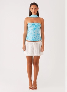 Detailed close-up of blue floral sequin embroidery on tube top and white eyelet skirt