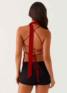 Detailed back view of red halter top featuring intricate criss-cross tie-up design and ribbon