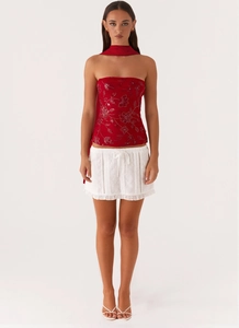 Detail of red sequin floral embroidery top and white lace tie-up mini skirt set