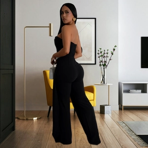 Detail of elegant black strapless jumpsuit with wide legs worn by model in chic interior
