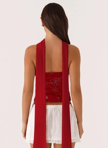 Detail of red backless sequin floral top with long chiffon ribbons and eyelet skirt