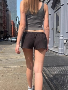 Damen Set mit Rippstrick-Oberteil und schwarzen Shorts von hinten im Freien gesehen