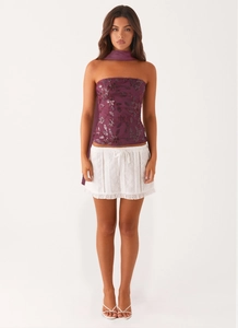 Detailed embroidery on purple sequin tube top paired with white eyelet mini skirt