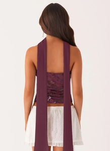 Detail view of burgundy sequined floral embroidery on a backless strapless crop top