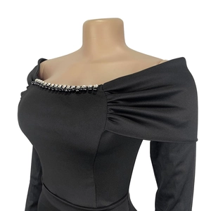 Detail of elegant black dress showing beaded square neckline and pleated shoulder design