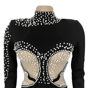 Detail of elegant black dress showing mesh patchwork and white pearl embellishments