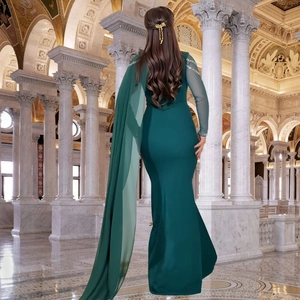 Détail de robe de soirée vert foncé avec cape à l'épaule et poignets ornés de sequins