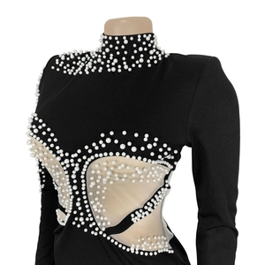 Close-up of elegant black dress featuring intricate white pearls and sheer mesh panels