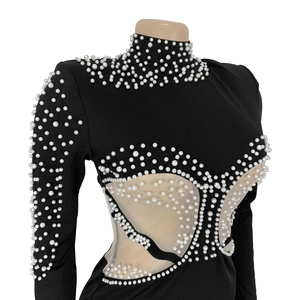 Detail of black dress featuring intricate white pearl beading and sheer mesh paneling