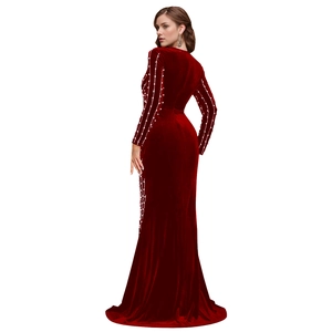 Rear view of long sleeve red velvet dress with pearl embellishments and slit hem