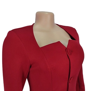 Detail of red fitted blouse with asymmetric square neckline and fabric covered buttons