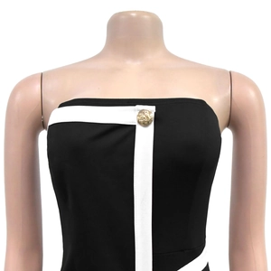 Detailed view of black tube dress with white contrast trim and golden lion button