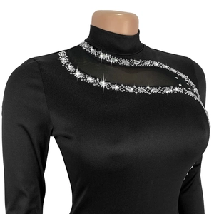 Détail de robe noire à manches longues avec découpe en maille et strass brillants