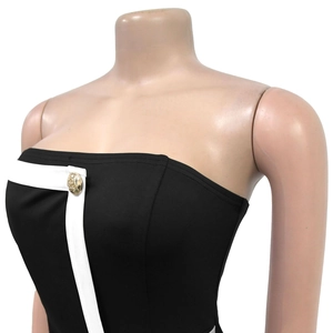 Detail of strapless romper featuring white contrast piping and a gold embossed button