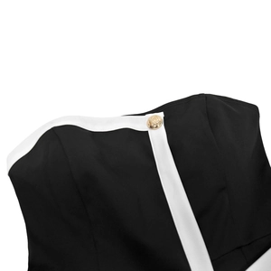 Detailed close-up of a black tube top neckline with white trim and a gold embossed button