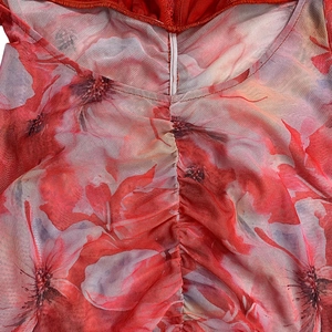 Detail aus rotem Mesh-Stoff mit Blumendruck, geraffter Textur und transparentem Finish