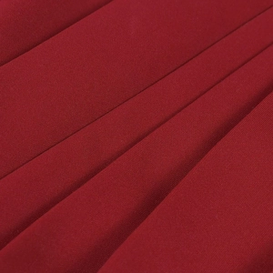 Detailed close-up of dark red pleated fabric with fine texture and deep elegant shadows