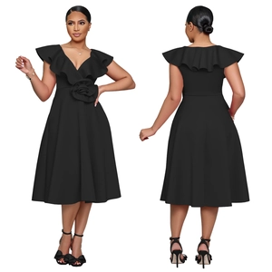 Detail of elegant black V-neck dress featuring ruffled shoulders and a large floral accent