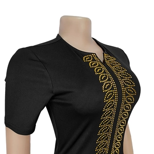 Détail d'une robe noire à manches courtes avec motifs de strass dorés sur le décolleté