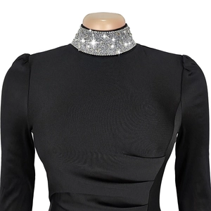 Détail de robe noire à manches longues avec col montant en strass et corsage plissé