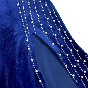 Detail of dark blue velvet dress featuring elegant slit with pearl and rhinestone fringes