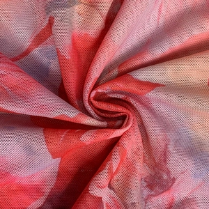 Detailaufnahme von bedrucktem Netzstoff mit lebhaften Blumenmustern und weichen Falten