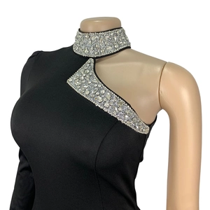 Detail of elegant black dress with asymmetric cutout and shimmering rhinestone trim
