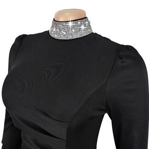 Détail d'une robe noire cintrée avec col montant orné de strass et manches bouffantes élégantes