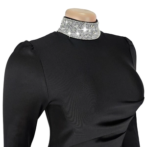 Détail du col montant avec strass sur une robe de soirée noire à manches longues