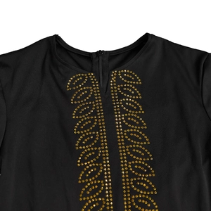Détail de la robe noire avec motifs de feuilles en strass dorés et fermeture éclair