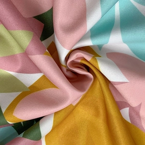Close-up of vibrant floral print fabric with silky texture and colorful abstract patterns