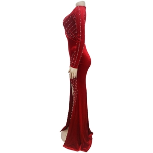 Detail view of red velvet dress featuring high side slit and radiant pearl beadwork