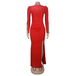 Détail d'une robe de soirée rouge à manches longues avec strass au col et fente haute