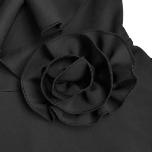 Macro detail of elegant black dress showing large 3D ruffle flower and premium fabric texture