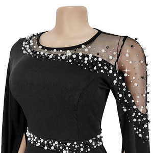 Close-up of elegant black dress with rhinestones and pearl embellishments on sheer mesh