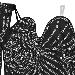Dettaglio dell'abito da sera nero con decorazioni complesse in strass e perle