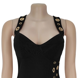 Détail du décolleté en cœur avec œillets dorés sur une robe moulante noire
