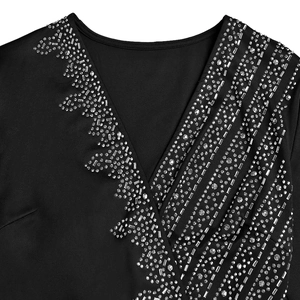 Close-up of elegant black V-neck dress with silver rhinestones and metal studs detail