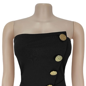 Close-up of strapless black dress featuring decorative gold lion head buttons on knit fabric
