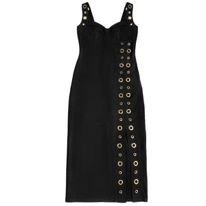 Détail d'une robe noire élégante avec œillets métalliques dorés et fente latérale