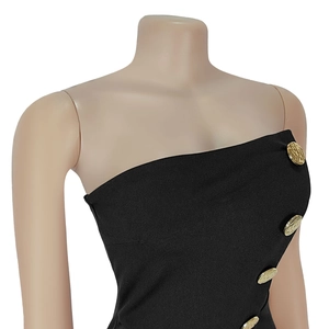 Detailed macro view of black textured fabric and vertical golden relief buttons on a dress