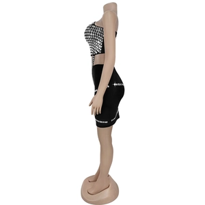 Détail d'un ensemble deux pièces noir avec crop top et mini-jupe à strass