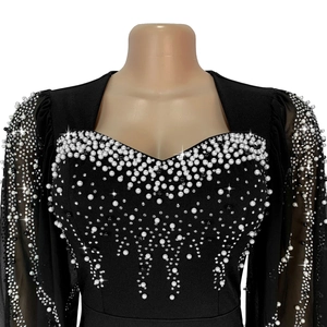 Détail de robe noire élégante avec encolure carrée ornée de perles et de strass brillants