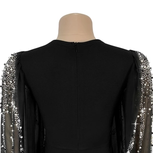 Détail de robe de soirée élégante avec manches en résille, perles et zip au dos