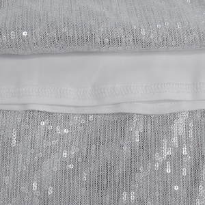 Macro detail of white sequin mesh fabric with silver circular sequins on evening dress