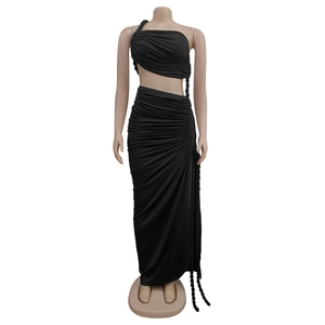 Détail d'un ensemble deux pièces noir avec crop top asymétrique et jupe longue froncée