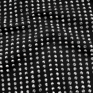 Détail du tissu en maille noire avec des strass argentés en motif de matrice