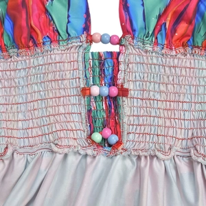 Detail eines bunten gesmokten Kleides mit abstraktem Druck und Makronen-Perlenakzenten