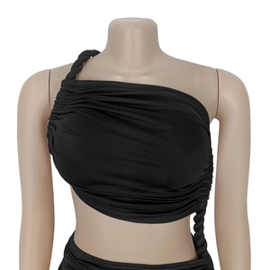 Détail du haut noir à une épaule avec bretelle tressée et texture plissée élégante