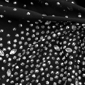 Macro detail of sparkling rhinestones on black sheer mesh fabric for sexy evening dress